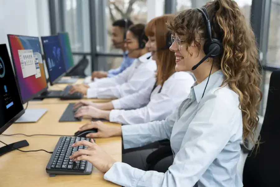 Call center customer support team working at computers with headsets for assistance and service.